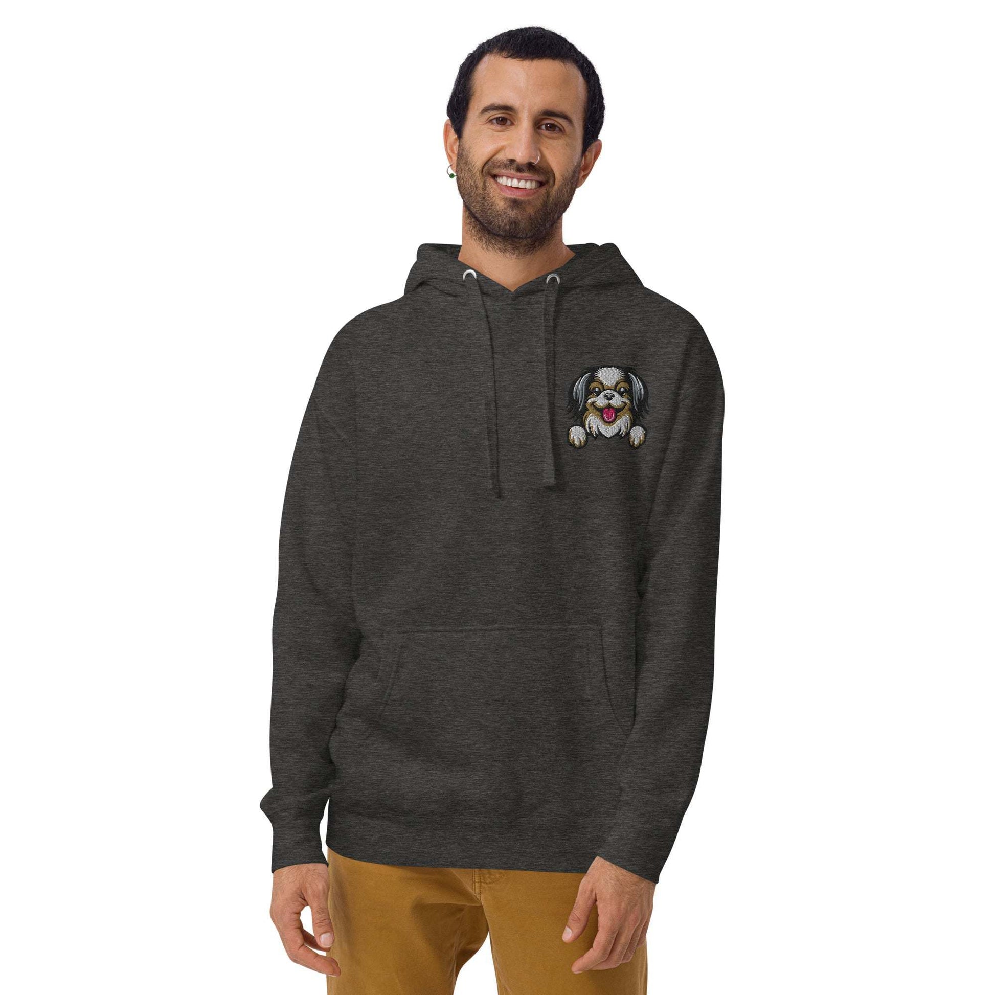 Unisex dark hoodie with embroidered Japanese Chin dog design on chest, featuring a pouch pocket and made from soft cotton blend.